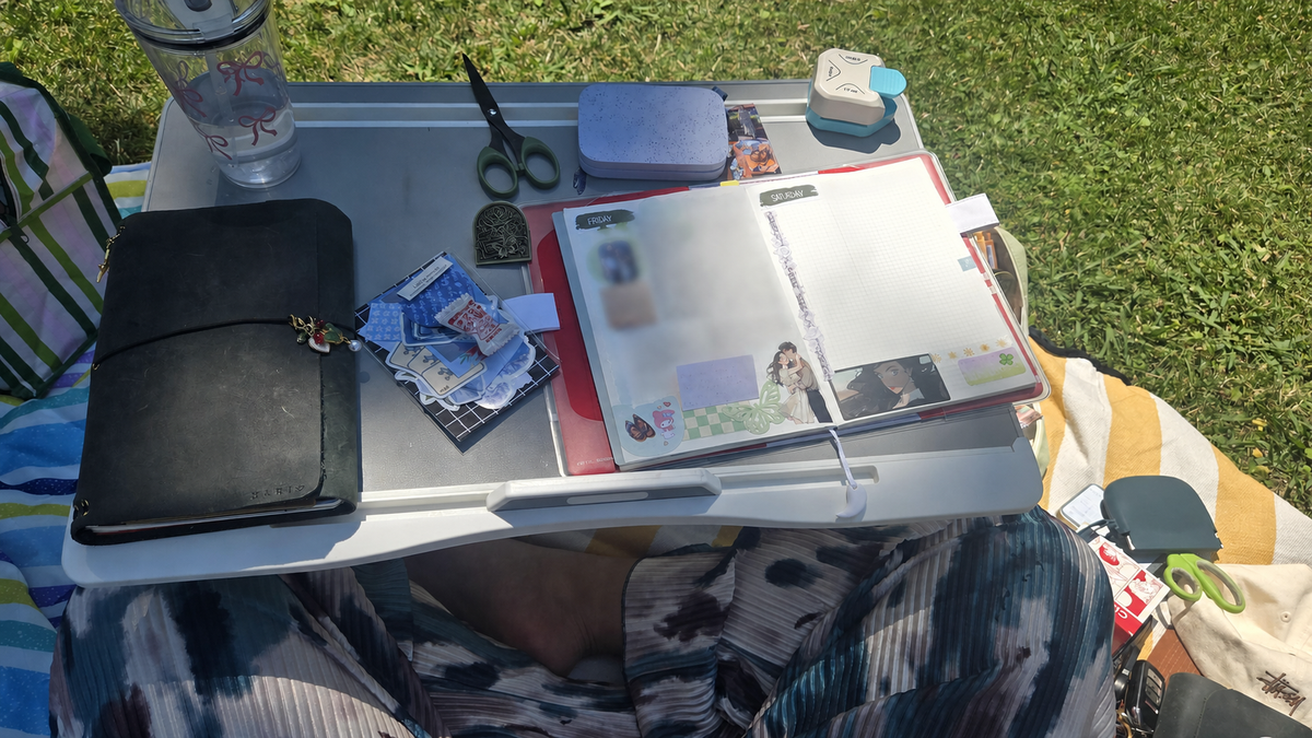Outdoor journaling setup with a MARIS leather journal and a decorated planner, with private handwriting blurred